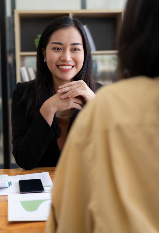 Smiling woman sitting across table from another person