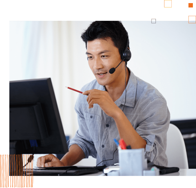 man wearing a telephone headset sitting in front of a computer