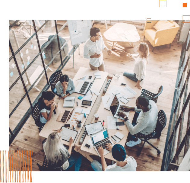 overhead of workers sitting at a table working on computers