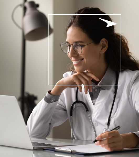 smiling woman looking at laptop screen while holding pen