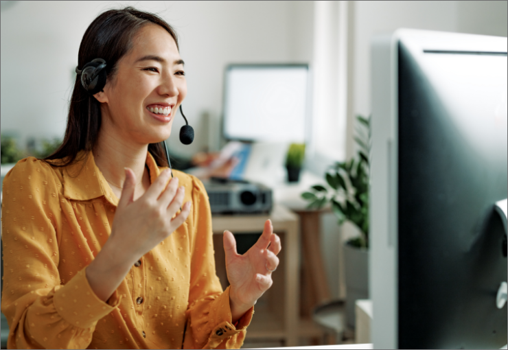 smiling woman wearing phone headset at computer