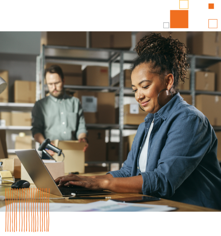 woman using laptop in a warehouse room of boxes